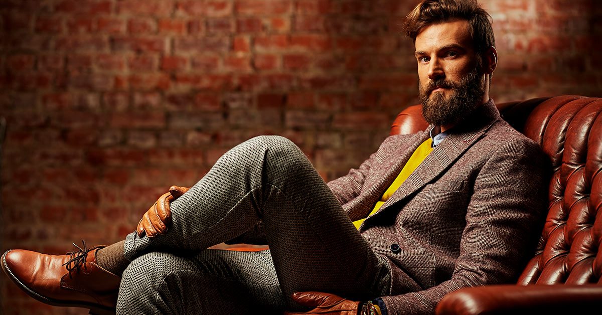 Man with full beard in a suit sitting in a leather chair