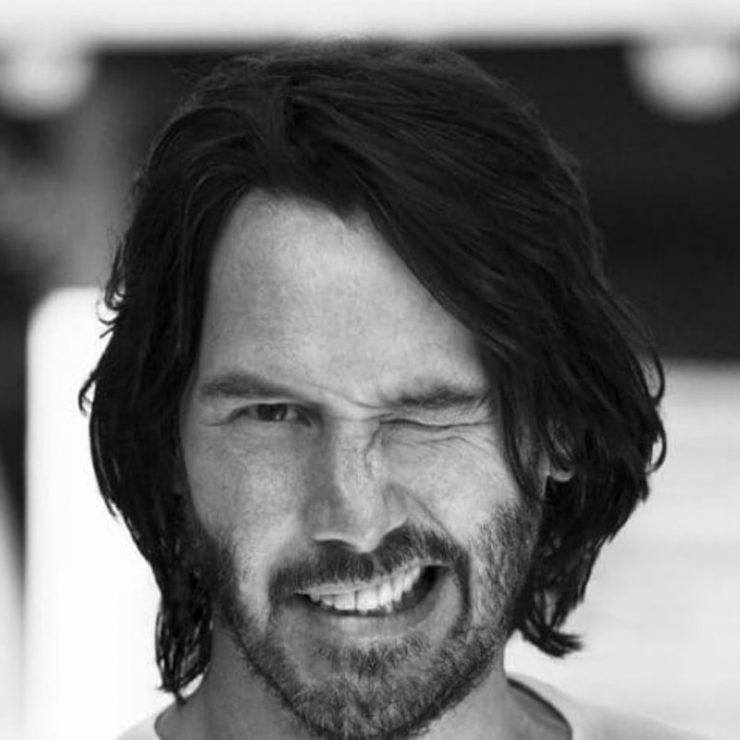 Keanu Reeves with a side-parted hairstyle. 